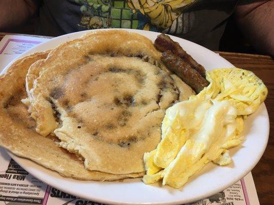 Cinnamon roll pancakes with scrambled eggs and cheese and sausage links.