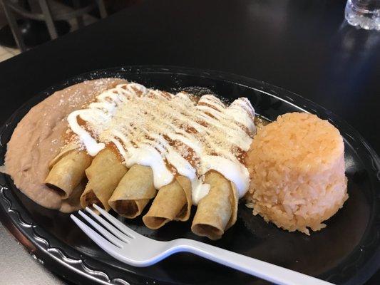 Potato flautas, entomatada style with tomato sauce, sour cream, and cheese. Served with rice and beans.