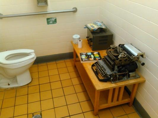 Men's bathroom with interacting radio and typewriter ( what's a typewriter??? ) in it.