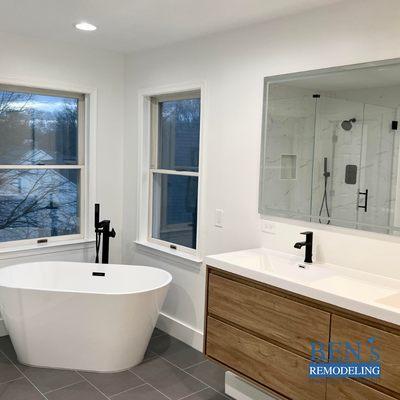 a remodeled bathroom , grey floor tiles, stand-alone tub , blackl finish, double sink vanity