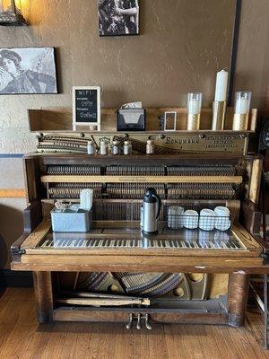 Old school piano where the creamer, spices and sweeteners are located.