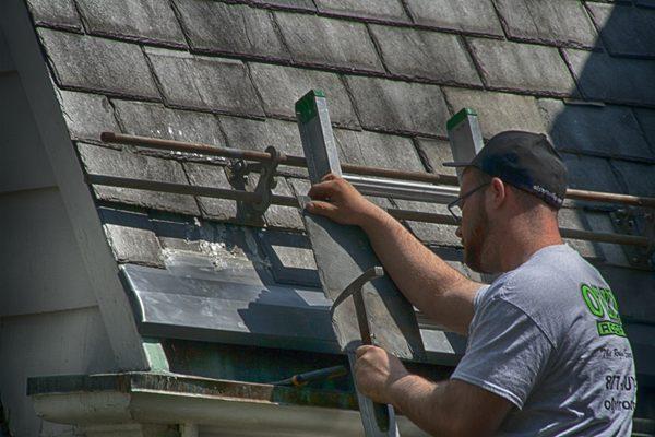 O'LYN Roofing contractor performing a roof replacement for a slate roof in Massachusetts.