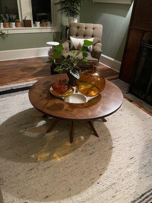 Coffee table with a glass top and bowl underneath.