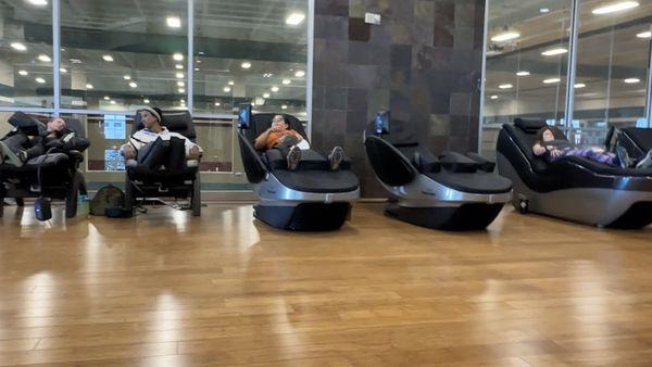 Interior of space showing massage chairs directly, facing stretching tables.