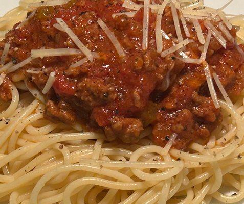 Spaghetti Bolognaise topped with course pepper and freshly grated parmesan cheese