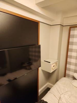 The wide screen TV is mounted alongside the bed and the safe mounted alongside that.