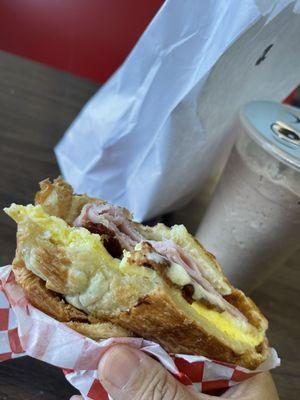 Bacon, Ham, cheese, egg croissant.   Iced Mocha in the background.