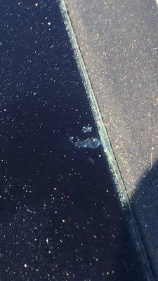 (Close up) Windshield glass defect on right side edge. This is the top of the glass. It appears to be a hole.