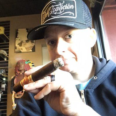 Kate (me!) smoking a La Coalicion by The Crowned Heads while wearing a cap by the same company.