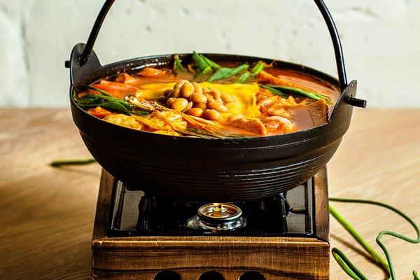 Army Stew (Budae-jjigae). Sausages, spam, kimchi, mushroom, beans, mini pork dumplings, ramen noodles
 topped with sliced cheese.