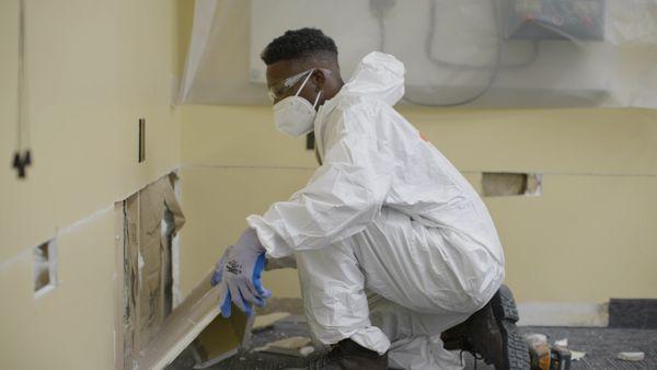 SERVPRO technician cutting drywall after flood damage.