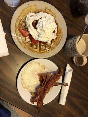 Belgian waffle with fresh strawberries. Added one egg fried and bacon