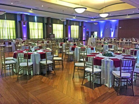 A display of the Young Main Lounge in Illinois Wesleyan University. There is around 8 round tables with red table decor