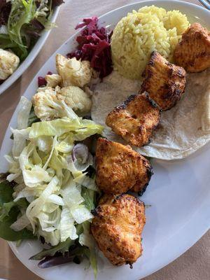 Chicken kabobs, salad, cabbage and another dish.