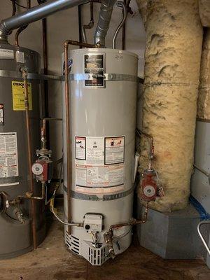 Old water heater out and new water heater in with recirculating line reconnected.