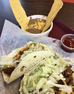 Two soft beef tacos with Mexican rice and a broken taco shell for dipping.