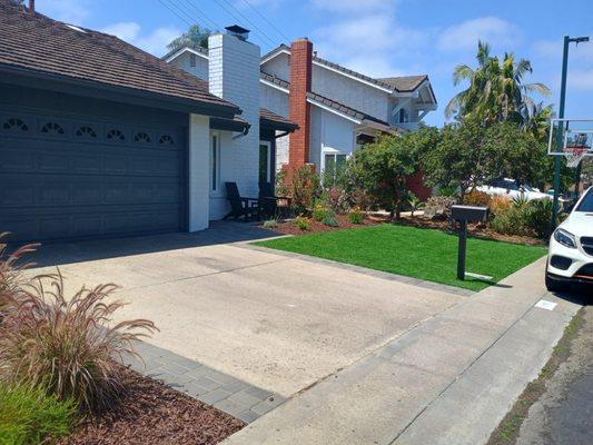 Triple green Turf and mulch area with 1 piece belgard paver extension on both side of driveway and leading up to the door step.