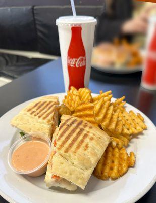 Tuscan Chicken panini with waffle fries and a drink.