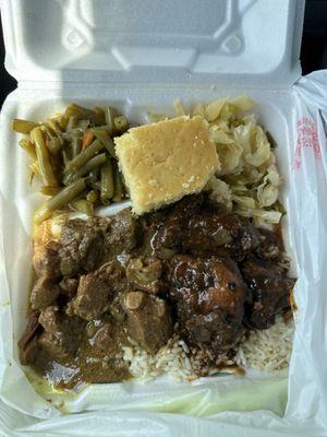 Combo plate: curry goat, jerk chicken over white rice, cabbage, green beans, and corn bread