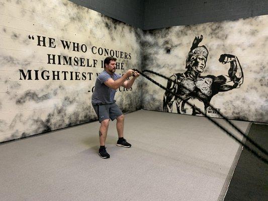 Akron member performing battle ropes in front of our new mural.