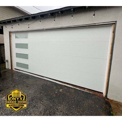 Behold our latest masterpiece: a custom garage door installation featuring sleek windows. Elevate your curb appeal with us today!