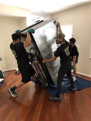 Enrico, Fred, and Paul trying to fit this refrigerator through the front doorway