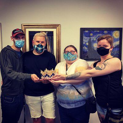 4 people standing holding crown