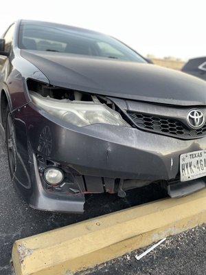 Car with dismantled headlight, broken bumper, and damaged grill.