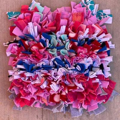 Snuffle mat made from a rubber dish mat and strips of fleece fabric.