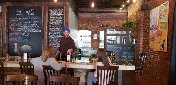 Warm and cozy interior with lots of seating and plants, local artists featured on the walls