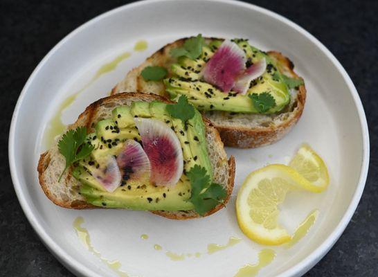 Avocado Toast, served on Firebrand's rustic sourdough. Hand sliced avocado topped with our herb salt, cilantro, seasame, watermelon radish