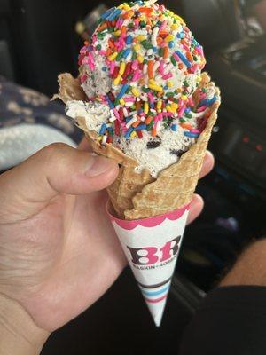 Waffle cone with Oreo cookie ice cream and rainbow sprinkles