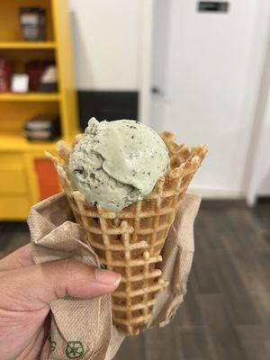 Half a scoop of mint chocolate chip in a waffle cone