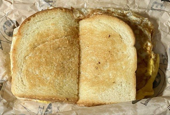 Breakfast sandwich on grilled sourdough with eggs, cheese, and mayonnaise.