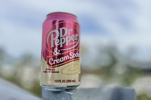 A single 12 ounce can of Dr Pepper and Cream Soda in the parking lot