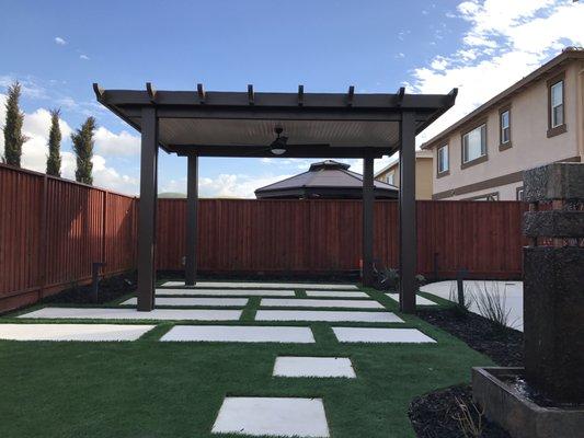 Freestanding patio cover with a pan roof. Equipped with a fan.