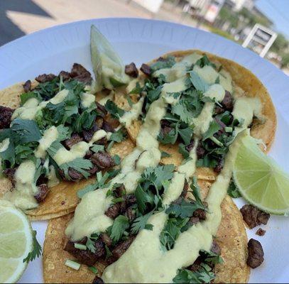 Fajita tacos with cilantro, green sauce, and limes