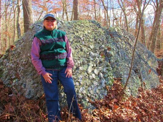 Scruffy person in front of scruffy rock