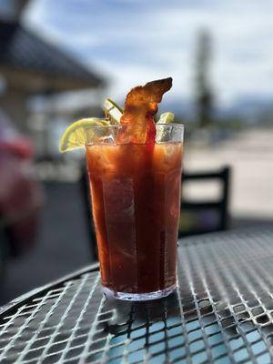 Bloody Mary garnished with lemon, lime, celery, olive, pickle, okra, bacon, pepperoncini, and a pepper jack wedge