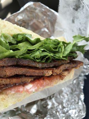 Thick slices of slab bacon, tomato, and Romain lettuce between toasted fresh, Crusty bread.