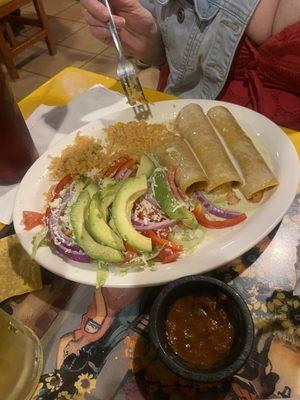 Seafood enchiladas with cheese sauce, rice with sliced avocados, lettuce and tomatoes.