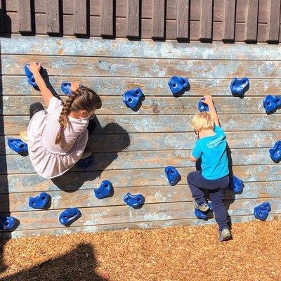 Kids hang from a climbing wall