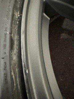 This is the tire tubercant (not curb rash).  that white fleck is where they took the paint off the wheel.