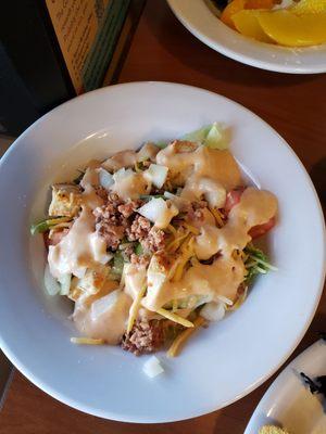 Garden salad topped with bacon and thousand island dressing