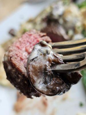 A fork holding a piece of The Filet Mignon main entrée.