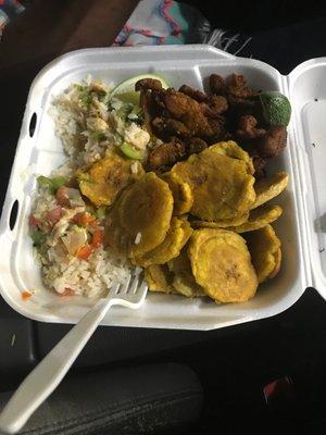 Dinner plate with pork, Tostones, and rice with shrimp salad on top of the rice.