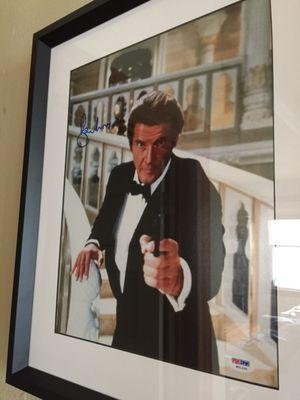 Signed Roger Moore photo with a deep frame and black trim on the white matte background.