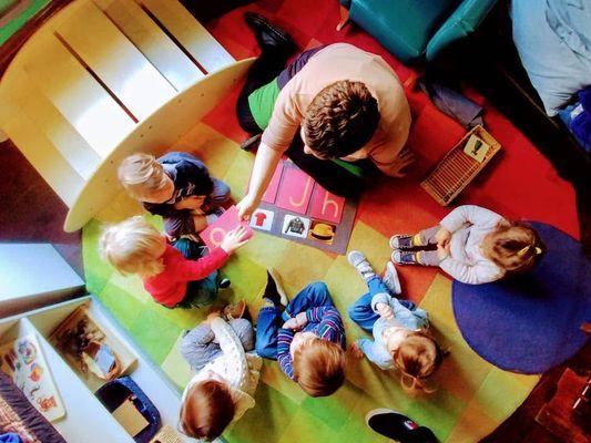 some of our Montessori toddler students being giving a language lesson using a material called the sandpaper letters