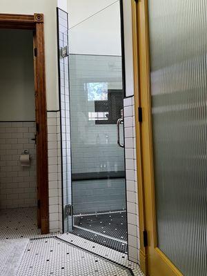 Contrasting penny tile bordered floors, walk in shower with bench and closet door