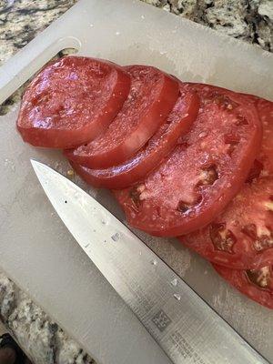 Sharpened knife and fresh sliced tomatoes.